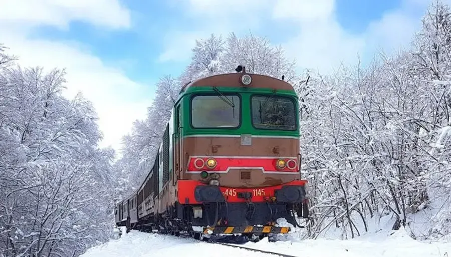 Historic Transiberiana d'Italia train crossing the snowy Apennine landscape