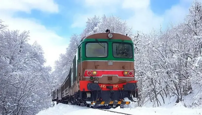Historic Transiberiana d'Italia train crossing the snowy Apennine landscape